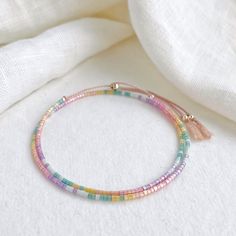 Our Shimmer Rainbow bracelet is made to catch the light when you move with rainbow coloured glass beads and silver sliding clasp to adjust length.  The silk cord is a pale pink colour and the beads are high quality glass beads in pink, peach, yellow, green, pale blue and lilac. Fits an average wrist size of up to 7 inches and tightens to 6.25in. Extends to maximum of 8.5in to fit over the widest part of the hand. If you have a small wrist and hands and would like a smaller bracelet size please contact me. Displayed in one of our pretty gift boxes, so fantastic as a present for a friend or to yourself! Check out the matching necklace https://www.etsy.com/uk/listing/1279385760/beaded-shimmer-rainbow-necklace-dainty Shipping Uk: 2-3 days - Royal Mail 48hr tracked International standard delive Pastel Beaded Bracelets For Gift, Pastel Beaded Bracelets Gift, Adjustable Rainbow Friendship Bracelets With Round Beads, Colorful Adjustable Friendship Bracelets With Beads, Adjustable Colorful Friendship Bracelets With Beads, Adjustable Colorful Friendship Bracelets, Rainbow Friendship Bracelets With Round Beads, Adjustable Pastel Beaded Bracelet, Adjustable Rainbow Braided Beaded Bracelet