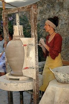 a woman is working on an art project with people sitting around her and looking at it