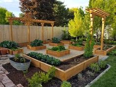 an outdoor garden with lots of plants and vegetables in the center, surrounded by wooden trelliss