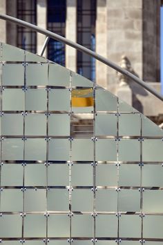 a yellow object sitting on top of a metal wall next to a stair case in front of a building