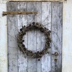 an old door with a wreath hanging on it's side and a wooden handle