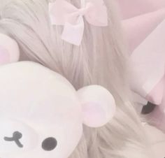 a white teddy bear with long blonde hair and a bow on it's head