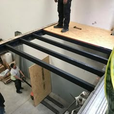 two men standing on top of a wooden floor in a room filled with boxes and other items