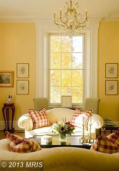 a living room filled with furniture and a chandelier hanging from the ceiling next to a window