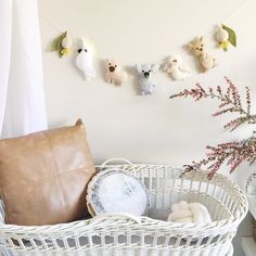 a basket with stuffed animals hanging from it's sides next to a pillow and pillows