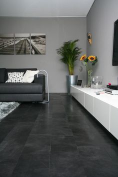 a living room with black tile floors and white furniture in front of a flat screen tv