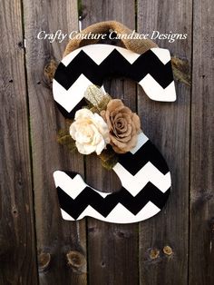 a black and white chevroned wooden sign with flowers on it's side