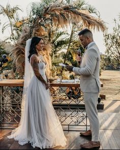 a bride and groom standing at the alter during their wedding ceremony with palm trees in the background