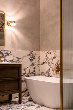 a bathroom with marbled walls and flooring, including a bathtub in the center