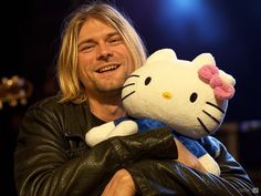 a man holding a hello kitty stuffed animal in his arms and smiling at the camera