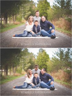 the family is posing for a photo in the middle of an empty road with trees behind them