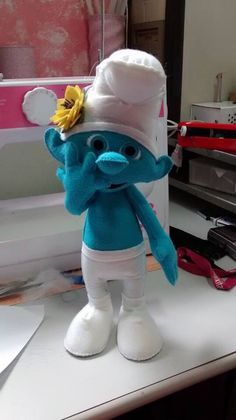 the smurch doll is standing on top of a sewing machine and wearing a chef's hat