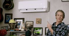 a man standing in front of a air conditioner with his hand up to the side