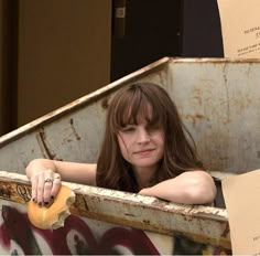 a woman sitting in the back of a dumpster with her hand on top of a piece of paper