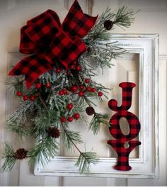 a red and black plaid christmas wreath hanging on a white door with pineconis