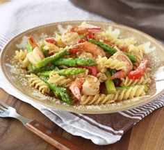 pasta with shrimp, asparagus and tomatoes on a plate next to a fork