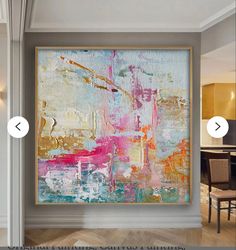 an abstract painting hanging on the wall next to a dining room table with chairs in it