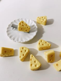 several pieces of cheese on a white plate with a knife and fork next to them