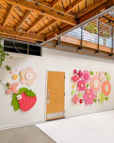 the wall is decorated with paper flowers and strawberries on it, as well as an open door