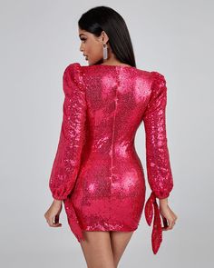 a woman wearing a pink sequin dress with long sleeves and tie at the waist