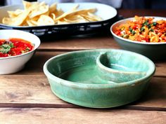 three bowls filled with different types of food on top of a wooden table next to other dishes