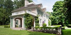 a large white house sitting in the middle of a lush green field with lots of trees