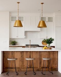 a kitchen with white cabinets and gold pendant lights