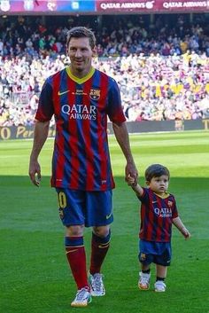 a man holding the hand of a small boy on a soccer field