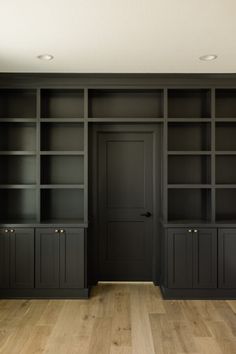 an empty room with black bookcases and wooden flooring is seen on the phone