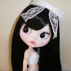 a doll with long black hair wearing a white dress