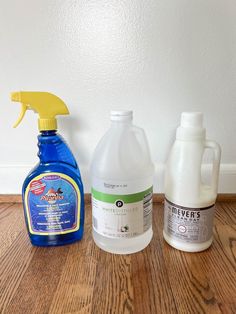 three different types of cleaning products sitting on a wooden floor next to each other, one is white and the other is blue