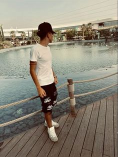 a man standing on a dock next to a body of water