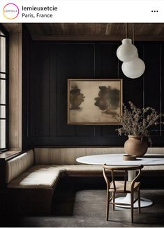 a dining room with black walls and wood paneling, a white table surrounded by two chairs