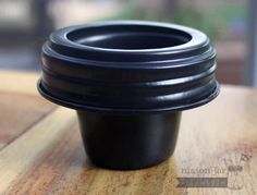 a black cup sitting on top of a wooden table