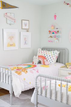 two twin beds in a white room with pictures on the wall above them and below them