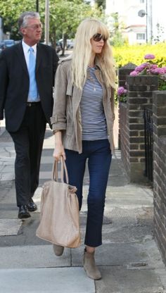 a woman walking down the sidewalk with a purse in her hand and a man behind her