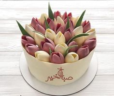 a white cake with pink and yellow tulips in it sitting on a plate