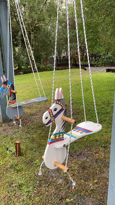 two toy horses on swings in the grass