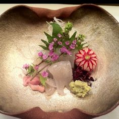 a metal bowl with flowers and ice cream in it