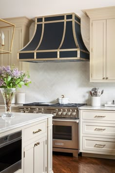 a kitchen with an oven, range hood and flowers in the vase on the counter