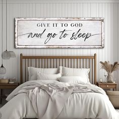 a bed with white sheets and pillows in front of a sign that says give it to god and go to sleep