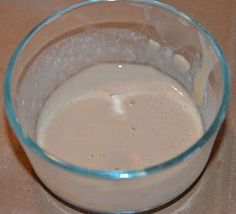 a glass filled with liquid sitting on top of a table next to a bottle of milk