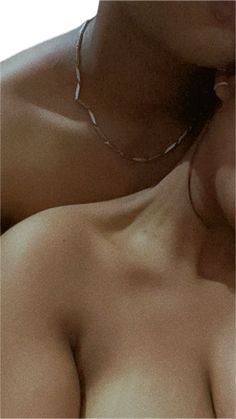 a close up of a woman's breast with no shirt and necklace on her neck