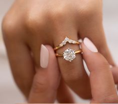 a woman's hand holding an engagement ring with two diamonds on the middle and one diamond in the middle