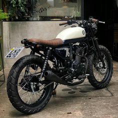 a white and black motorcycle parked in front of a building next to a planter