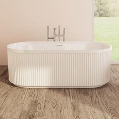 a large white bathtub sitting on top of a wooden floor next to a window