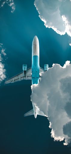 an airplane is flying in the sky with clouds behind it and blue water below them