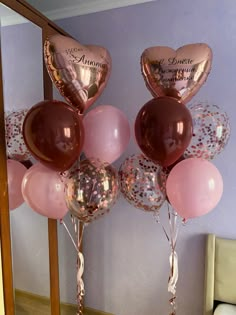 some pink and gold balloons are in front of a mirror with the names of two people on them