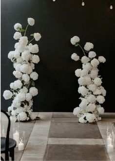 two tall white flowers sitting on top of a table next to candles and vases