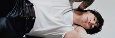 a man laying on his back next to a black bag and wearing a white shirt